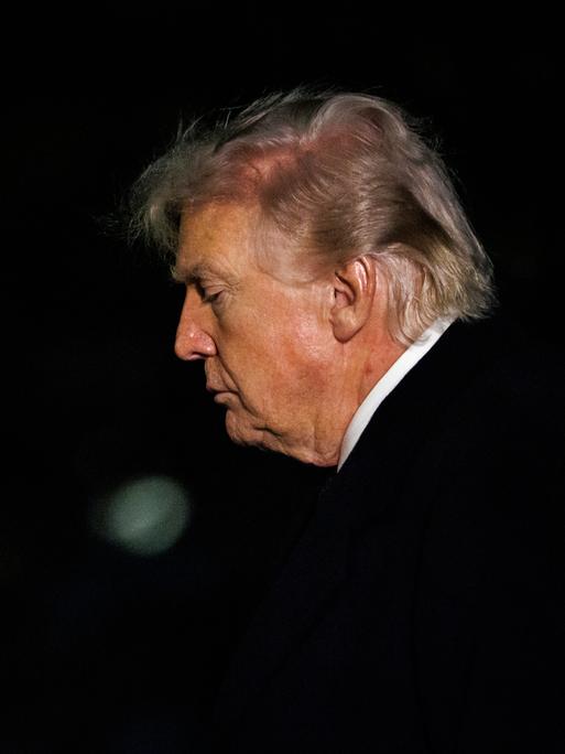 Das Foto zeigt das Gesicht von Donald Trump im Profil, als er in der Dunkelheit ins Weiße Haus in Washington zurückkehrt.