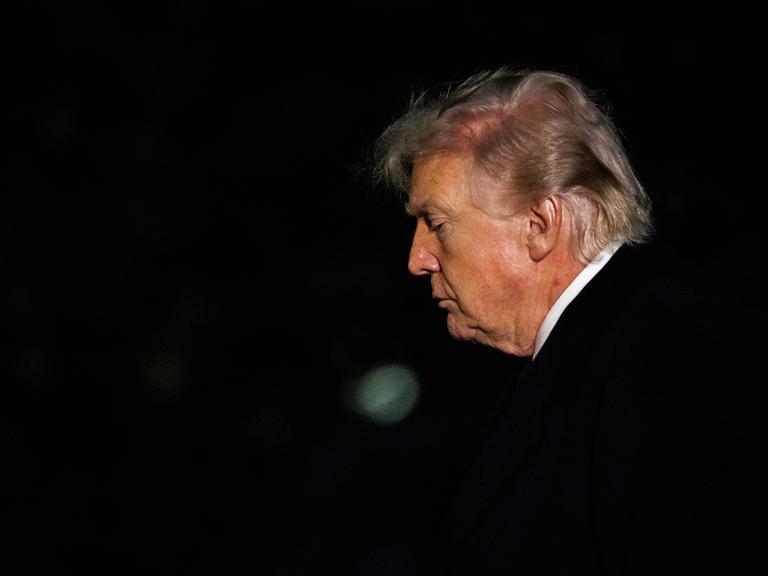 Das Foto zeigt das Gesicht von Donald Trump im Profil, als er in der Dunkelheit ins Weiße Haus in Washington zurückkehrt.