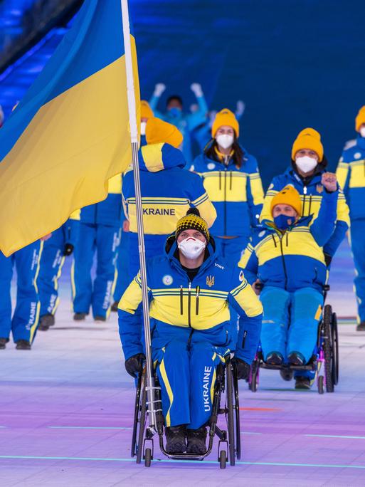 Maksym Yarovyi, Fahnenträger der Ukraine, zieht mit der Mannschaft aus der Ukraine bei der Eröffnungsfeier der Paralympics in das Stadion ein.