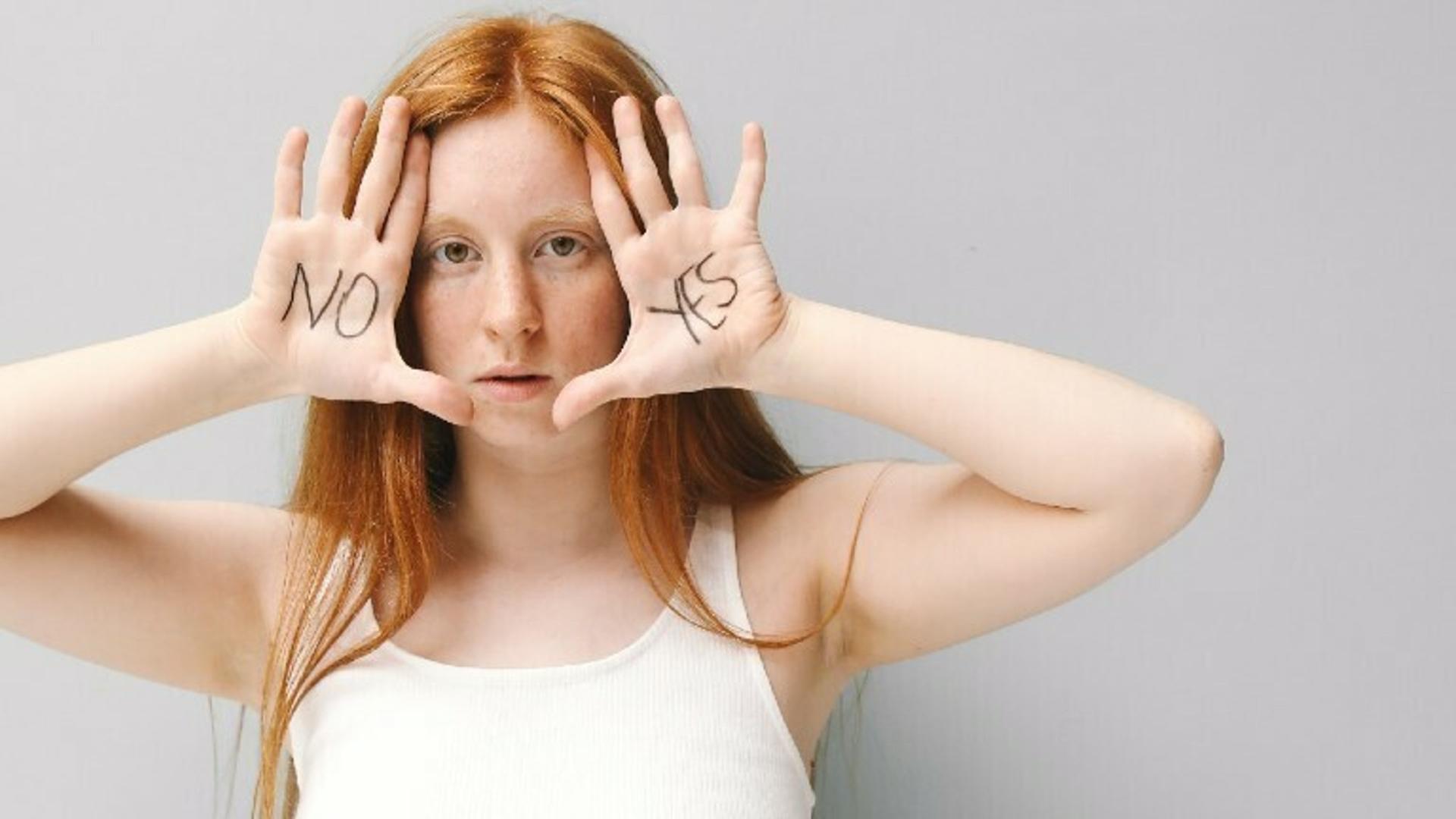 Eine Frau hält ihre Hände an das Gesicht. Auf einer Hand steht "Nein" auf der anderen "Ja".