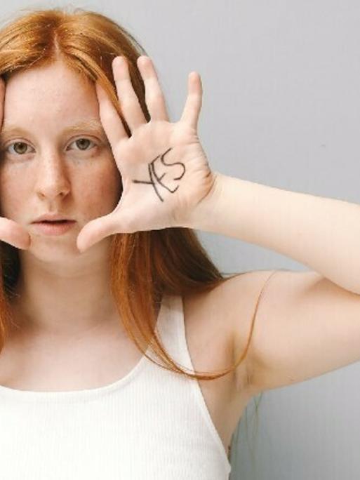 Eine Frau hält ihre Hände an das Gesicht. Auf einer Hand steht "Nein" auf der anderen "Ja".