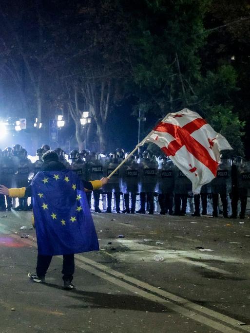 DIESES FOTO WIRD VON DER RUSSISCHEN STAATSAGENTUR TASS ZUR VERFÜGUNG GESTELLT. Ein Demonstrant mit Europa- und Georgienflagge steht vor einer Reihe von Sicherheitskräften.