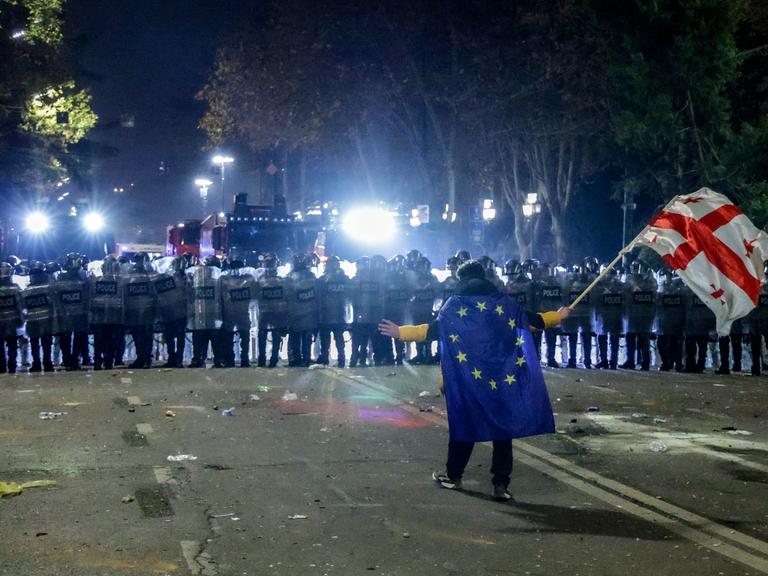 DIESES FOTO WIRD VON DER RUSSISCHEN STAATSAGENTUR TASS ZUR VERFÜGUNG GESTELLT. Ein Demonstrant mit Europa- und Georgienflagge steht vor einer Reihe von Sicherheitskräften.