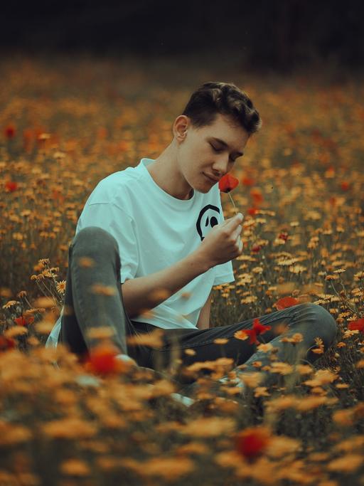 Junger Mann riecht an einer Blume.