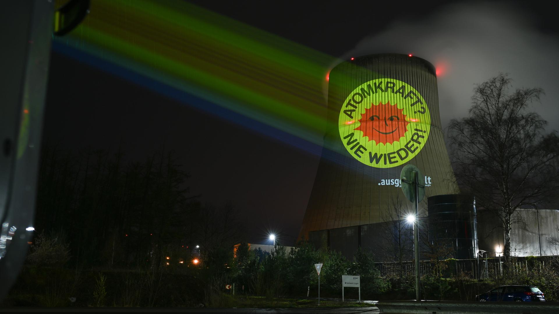 Aktivisten der Anti-Atom-Bewegung projizieren eine große Anti-Atom-Sonne auf den Kühlturm des Atomkraftwerkes Emsland. 