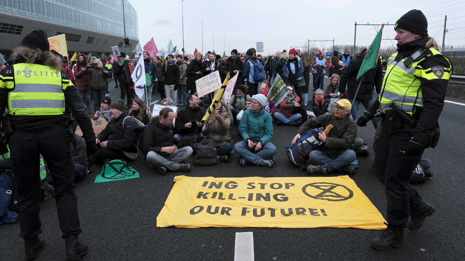 Polizisten sprechen mit Klimaaktivisten, die auf dem Asphalt sitzen. Polizisten sprechen mit Klimaaktivisten, die auf dem Asphalt sitzen.