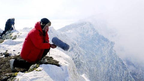 Der Regisseur Werner Herzog auf dem Gipfel des Mount Erebus in Schnee und Eis, mit einem Mikrofon in der Hand, 2007.