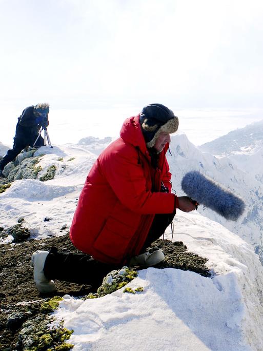 Der Regisseur Werner Herzog auf dem Gipfel des Mount Erebus in Schnee und Eis, mit einem Mikrofon in der Hand, 2007.