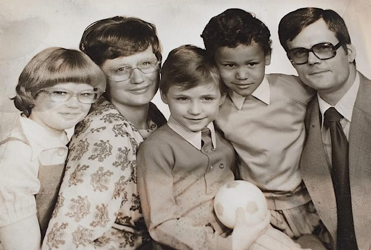 Ein Familienfoto mit Mutter, Vater und drei Kindern. Alle sind weiß, bis auf einen.