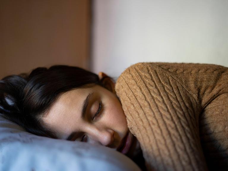 Eine junge Frau schläft im Bett.