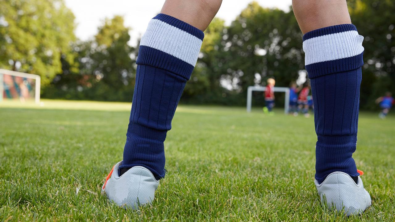 Ein Junge steht auf einem Fußballplatz und trainiert (Symbolbild).