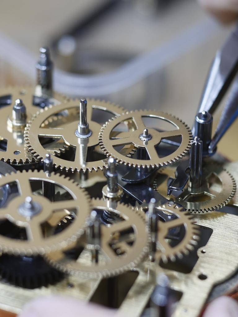 Zu sehen ist die Zange eines Uhrmachermeisters, der die Zahnräder eines Uhrwerks einstellt. 
