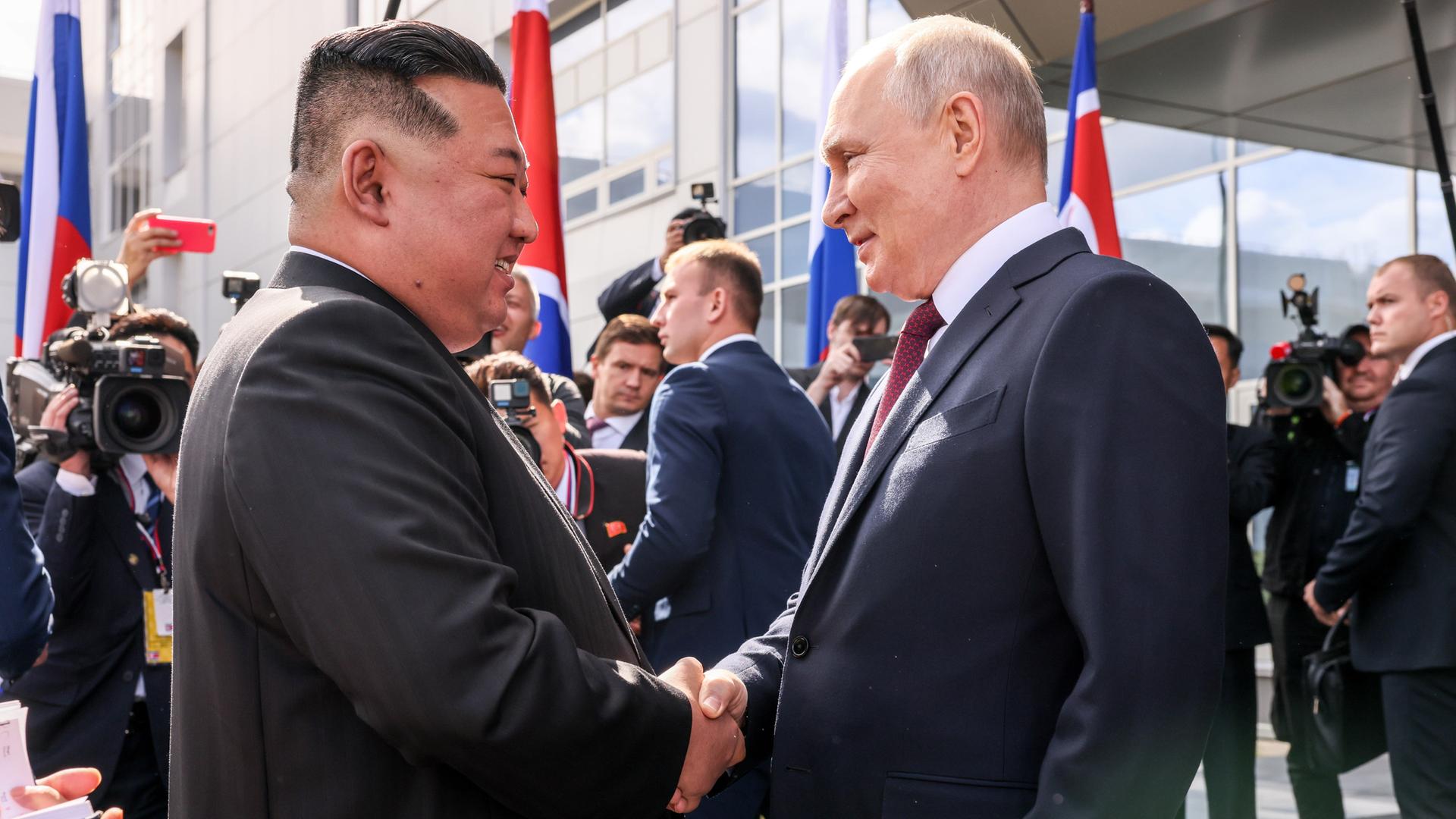 Wladimir Putin und Kim Jong Un reichen sich die Hände.