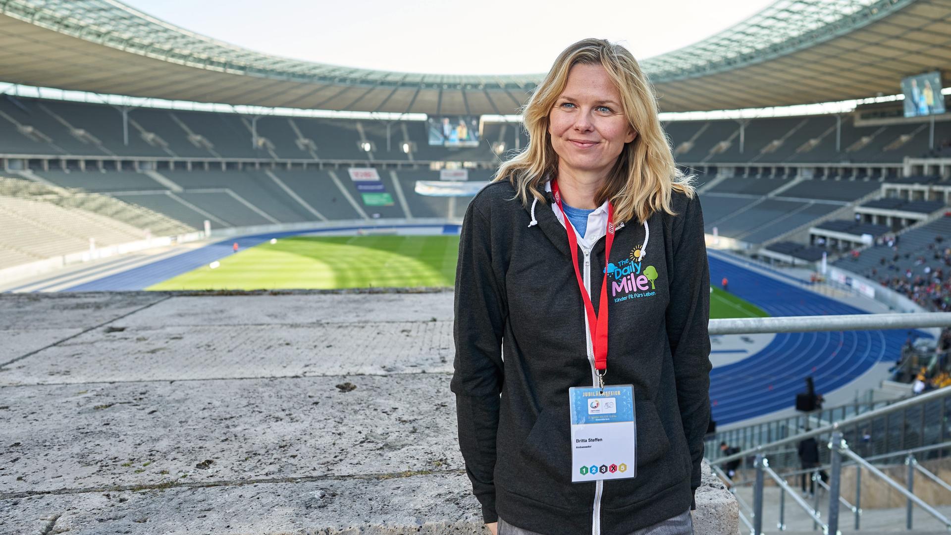 Eine große blonde Frau mit grauhaarigen Jeans in einem Sportstadium