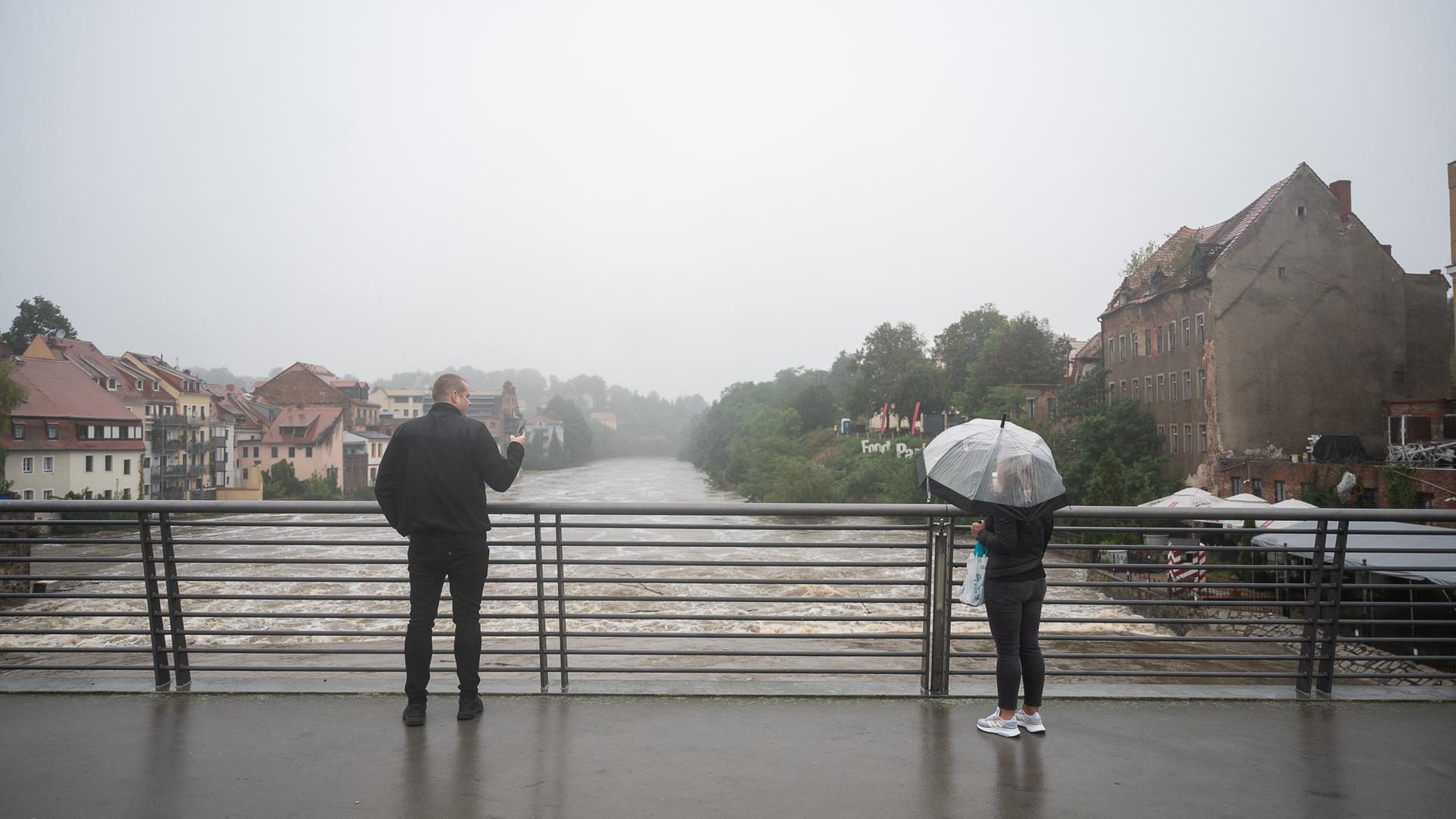 Polen, Zgorzelec: Zwei Passanten beobachten das Hochwasser der Neiße von der Altstadtbrücke aus. 