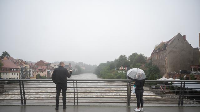 Polen, Zgorzelec: Zwei Passanten beobachten das Hochwasser der Neiße von der Altstadtbrücke aus. 