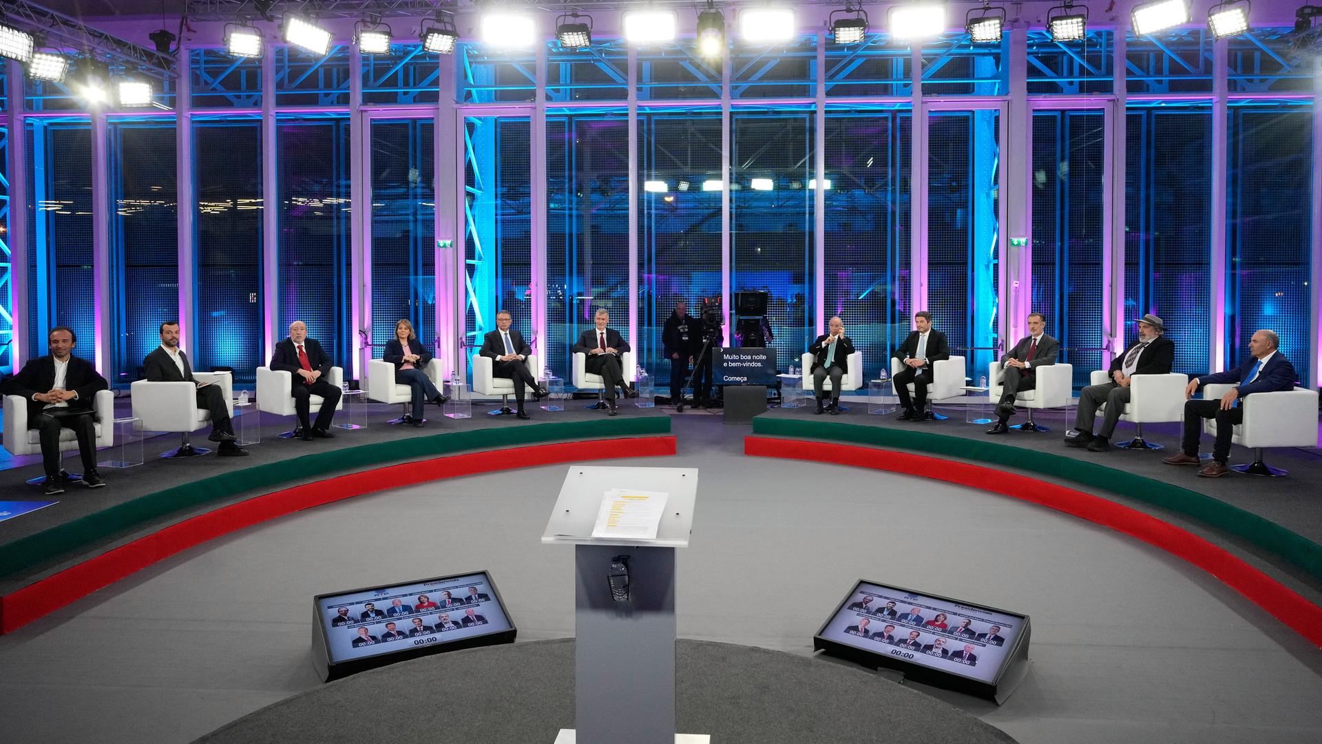 Die elf Kandidaten sitzen bei einer Debatte nebeneinander in einem Fernsehstudio.
      