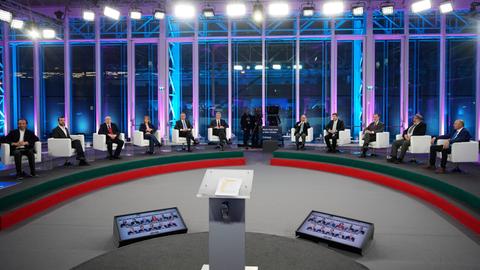 Die elf Kandidaten sitzen bei einer Debatte nebeneinander in einem Fernsehstudio.
      