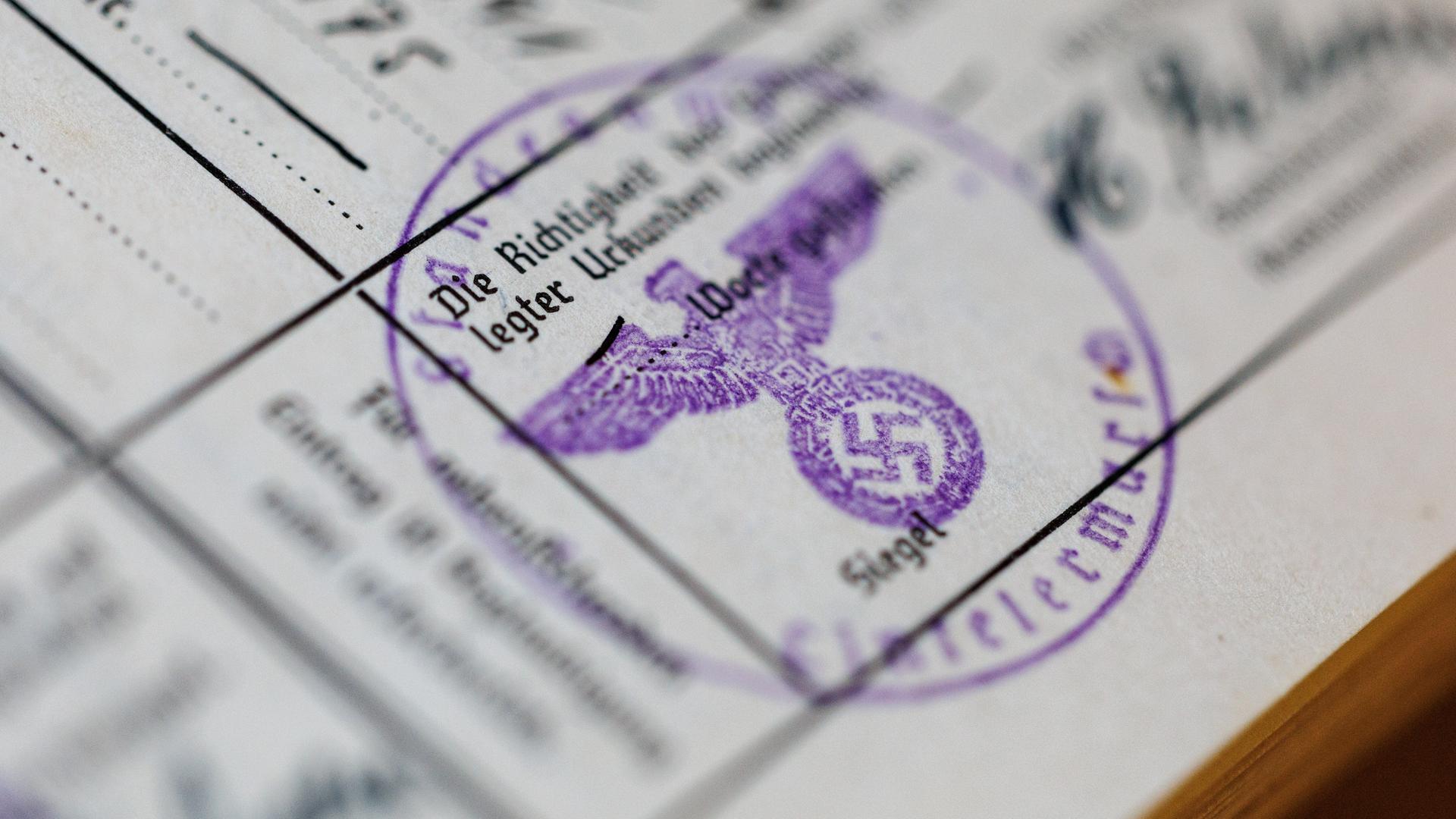 Ein Siegelstempel mit dem Parteiadler mit Hakenkreuz ist in einem Ahnenpass aus dem dritten Reich zu sehen. 