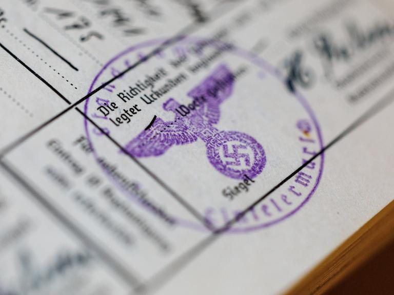 Ein Siegelstempel mit dem Parteiadler mit Hakenkreuz ist in einem Ahnenpass aus dem dritten Reich zu sehen. 