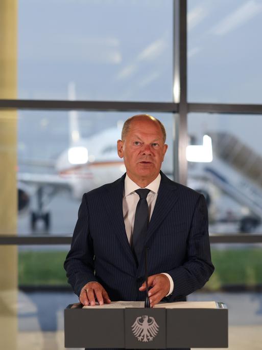 Bundeskanzler Olaf Scholz spricht bei einer Pressekonferenz auf einem Flughafen. 