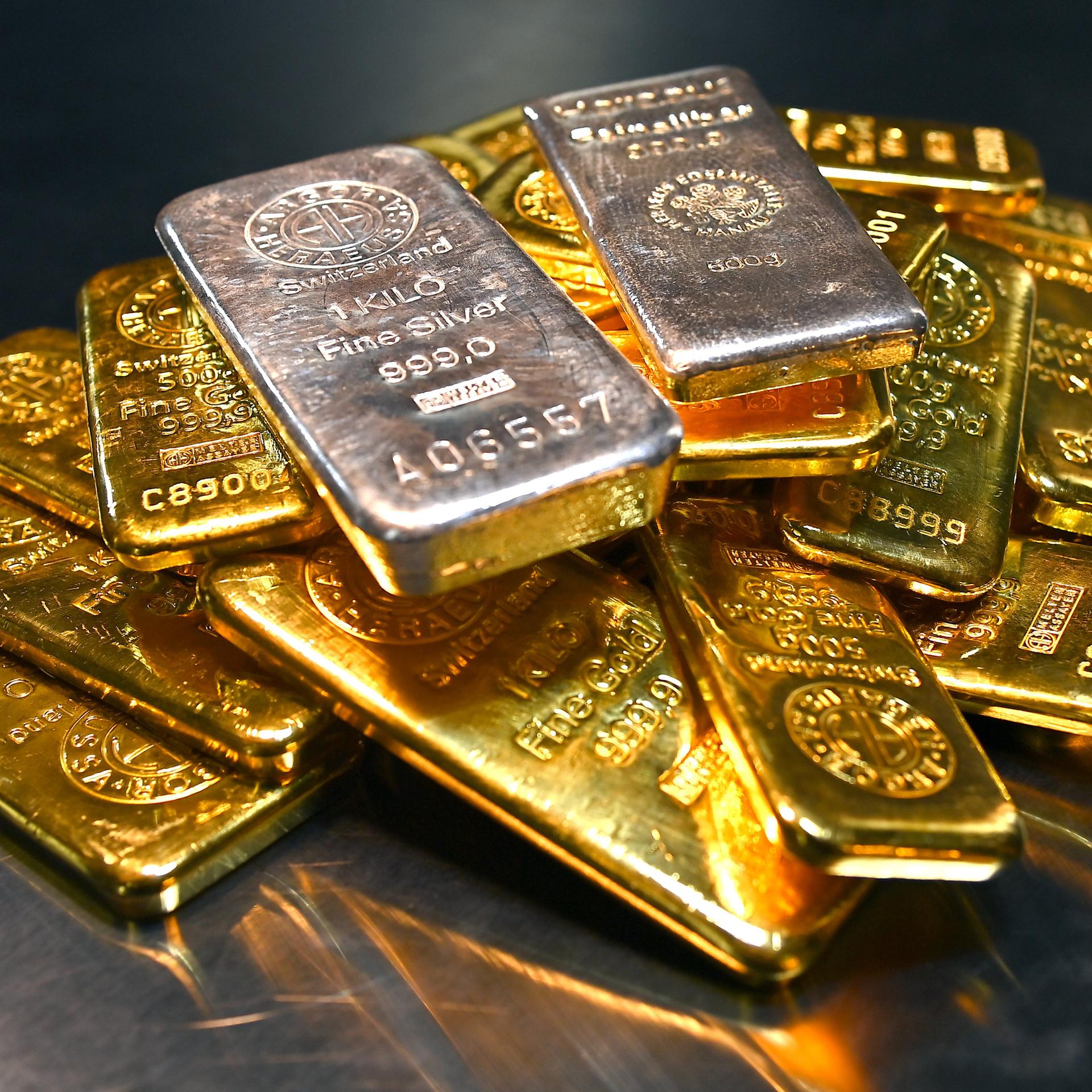 Goldbarren und Feinsilberbarren liegen übereinander.