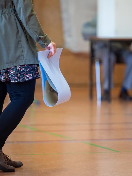 Eine wahlberechtigte Frau wartet in einem Wahllokal mit ihren Stimmzetteln in der Hand auf die Stimmabgabe. Die Europawahl begann am 6. Juni und in Deutschland wird am 9. Juni gewählt. In Brandenburg sind Kommunalwahlen und zeitgleich die Europawahl.