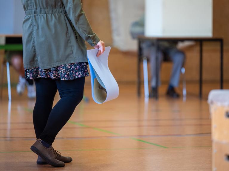 Eine wahlberechtigte Frau wartet in einem Wahllokal mit ihren Stimmzetteln in der Hand auf die Stimmabgabe. Die Europawahl begann am 6. Juni und in Deutschland wird am 9. Juni gewählt. In Brandenburg sind Kommunalwahlen und zeitgleich die Europawahl.