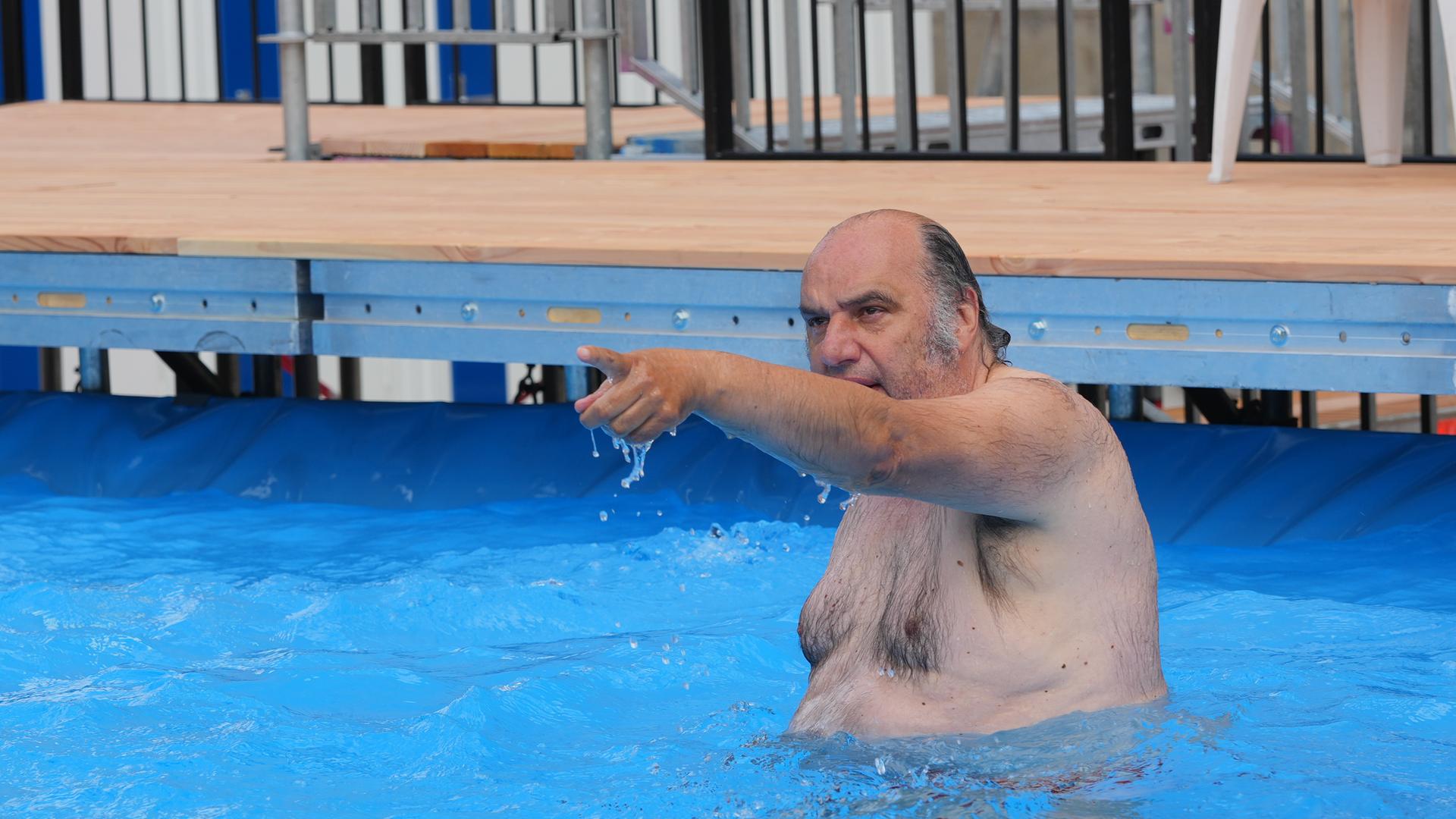 Intendant Matthias Lilienthal steht im Wasser des öffentlichen Schwimmbeckens vor der Volksbühne am Rosa-Luxemburg-Platz.
