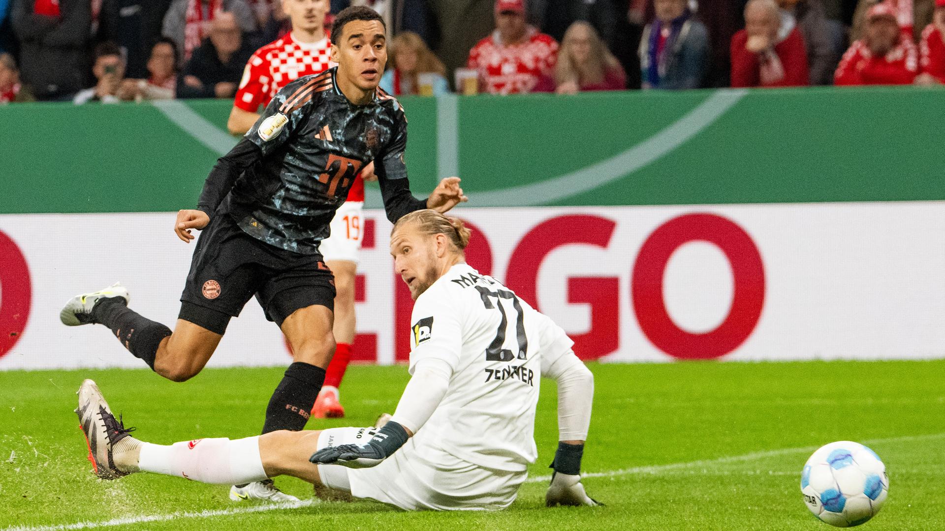 FC-Bayern-Spieler Jamal Musiala (l.) und Mainz-05-Torwart Robin Zentner beim 1:0