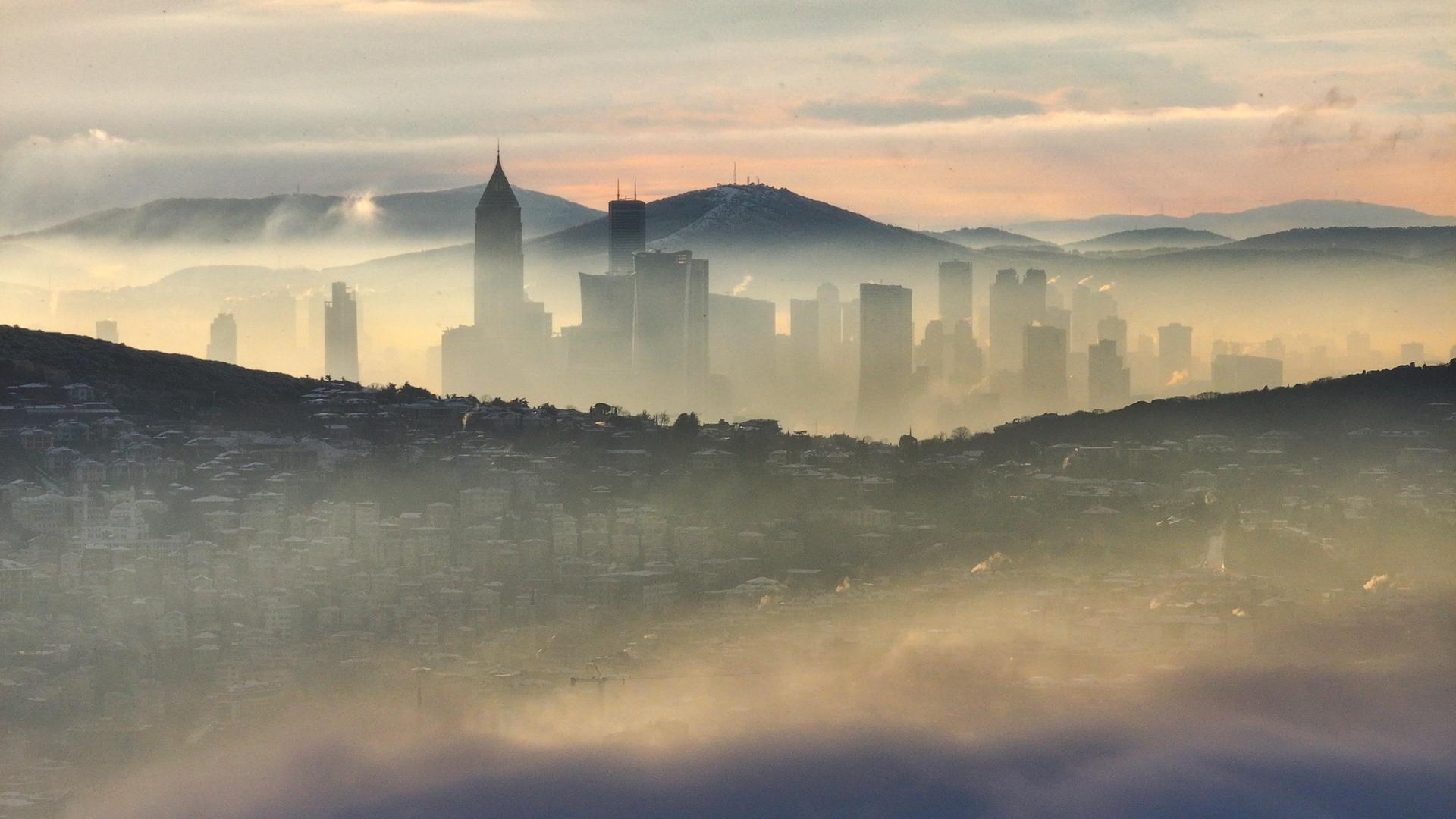 Über Istanbul liegt am Morgen eine Nebelschicht, dazwischen schauen Gebäude hervor.