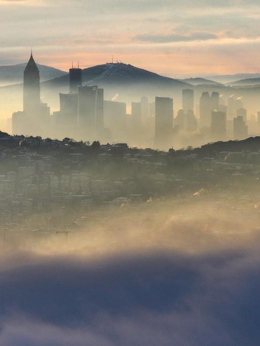 Über Istanbul liegt am Morgen eine Nebelschicht, dazwischen schauen Gebäude hervor.