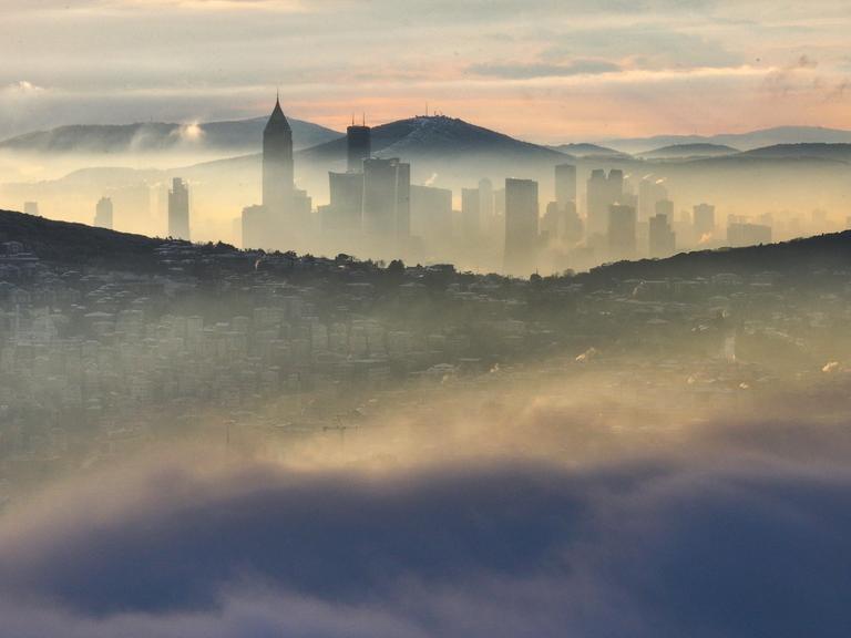 Über Istanbul liegt am Morgen eine Nebelschicht, dazwischen schauen Gebäude hervor.