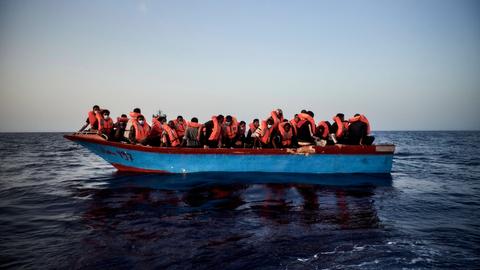 Flüchtlinge mit Rettungswesten auf einem überfüllten Boot im Meer.