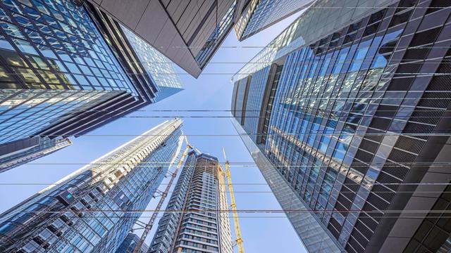 Blick nach oben zwischen Bankhochhaustürmen in Frankfurt am Main in den blauen Himmel.
