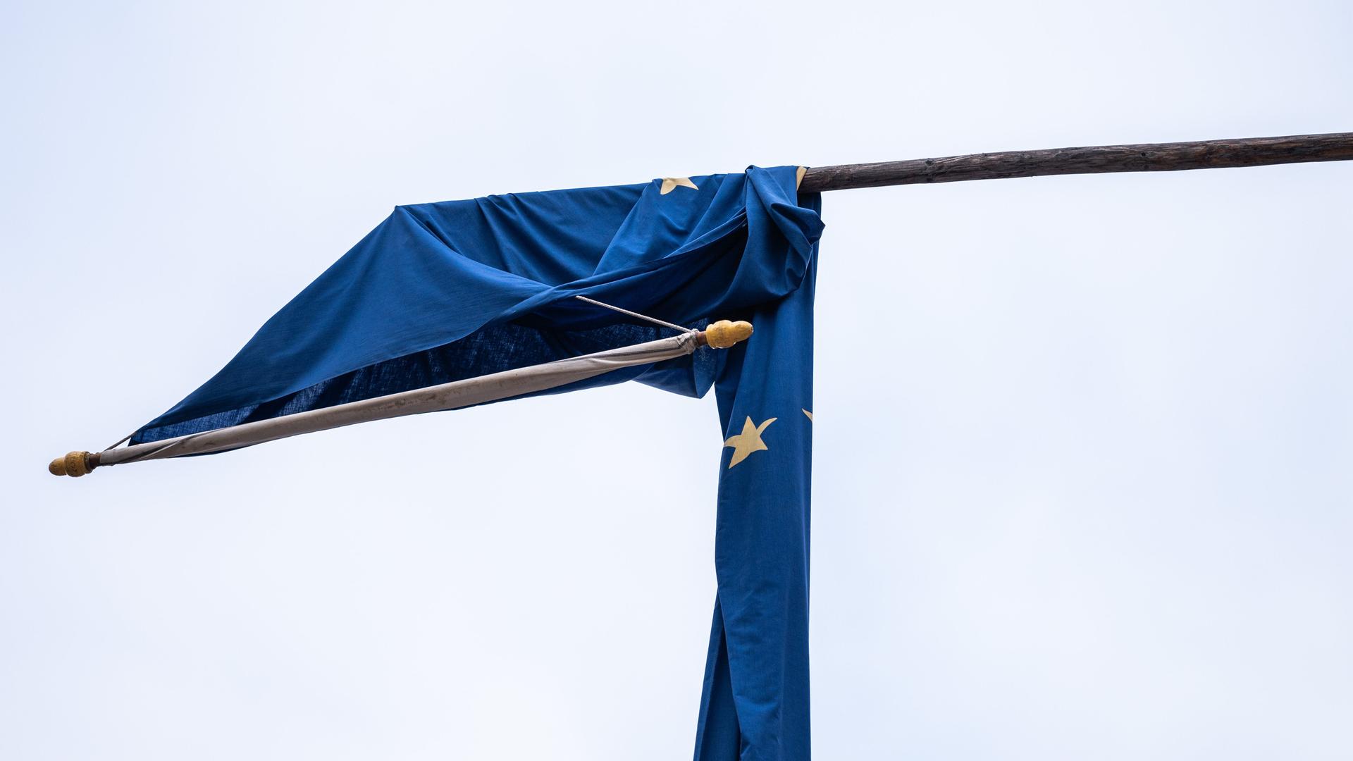 Eine Europaflagge hängt durch den Wind an einem Wahllokal in der Fußgängerzone Rottweil über einem Mast.