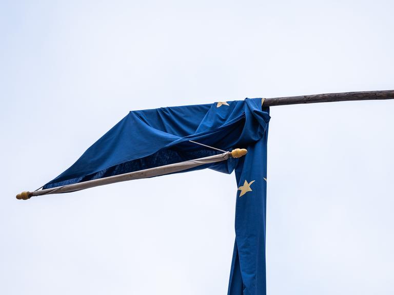 Eine Europaflagge hängt durch den Wind an einem Wahllokal in der Fußgängerzone Rottweil über einem Mast.