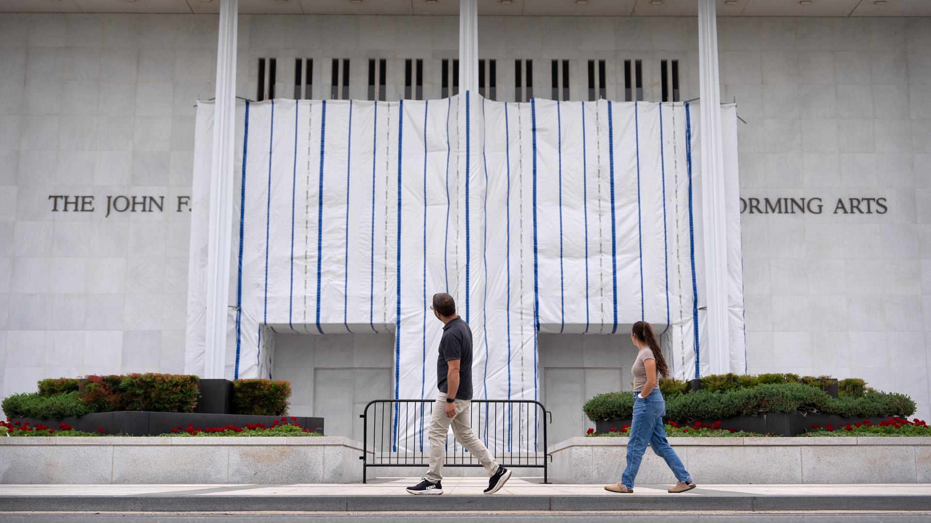 Besucher gehen am Freitag, dem 19. Juni 2026, in Washington am John F. Kennedy Center for the Performing Arts vorbei, dessen Schild weiterhin mit einer Plane abgedeckt ist. 