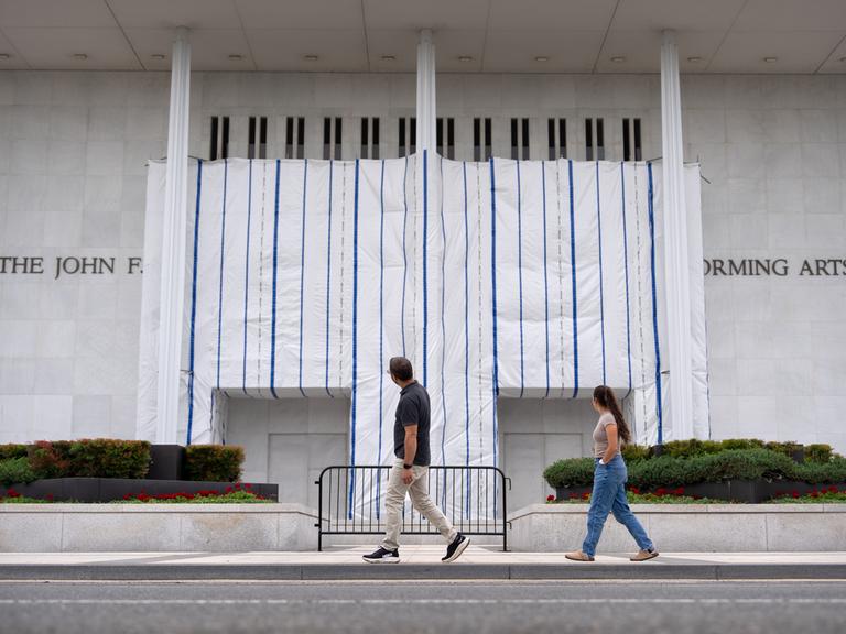 Besucher gehen am Freitag, dem 19. Juni 2026, in Washington am John F. Kennedy Center for the Performing Arts vorbei, dessen Schild weiterhin mit einer Plane abgedeckt ist. 