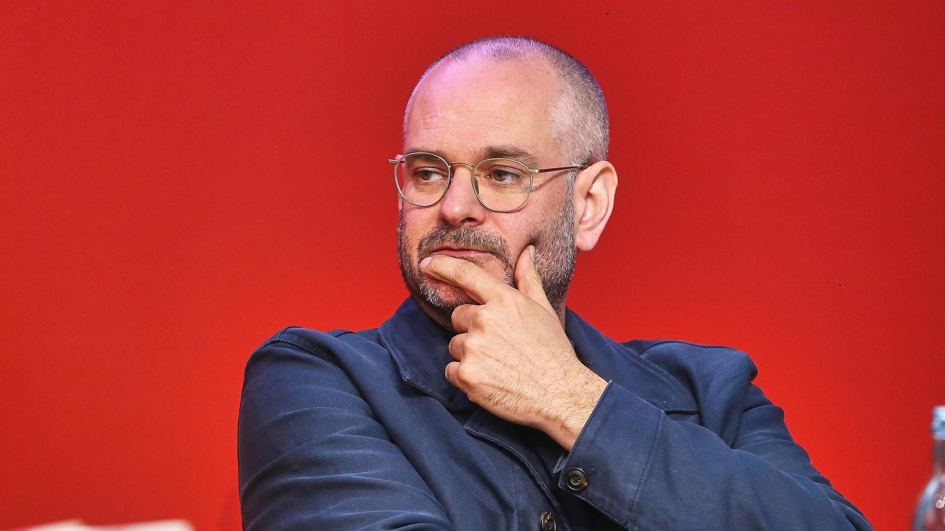 Jonas Lüscher schaut nachdenklich zur Seite, er hält die linke Hand am Kinn. Jonas Lüscher schaut nachdenklich zur Seite, er hält die linke Hand am Kinn.