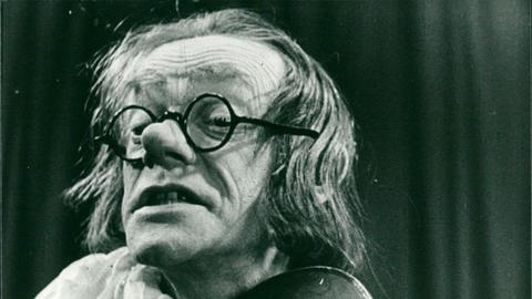 Die Abbildung zeigt den deutschen Komiker Karl Valentin auf einer Bühne mit einer Violine.