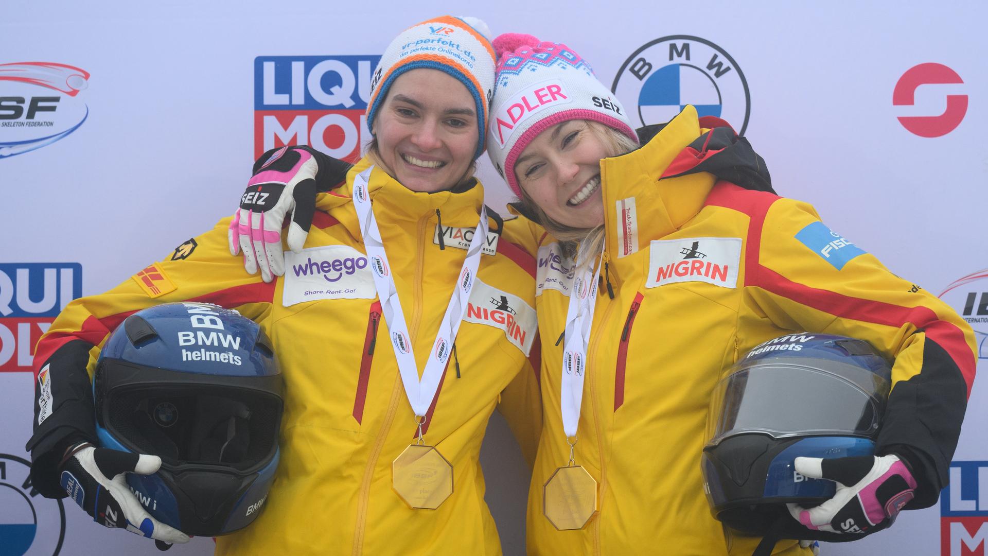 Laura Nolte und Neele Schuten tragen gelbe Sportanzüge und lachen in die Kamera.