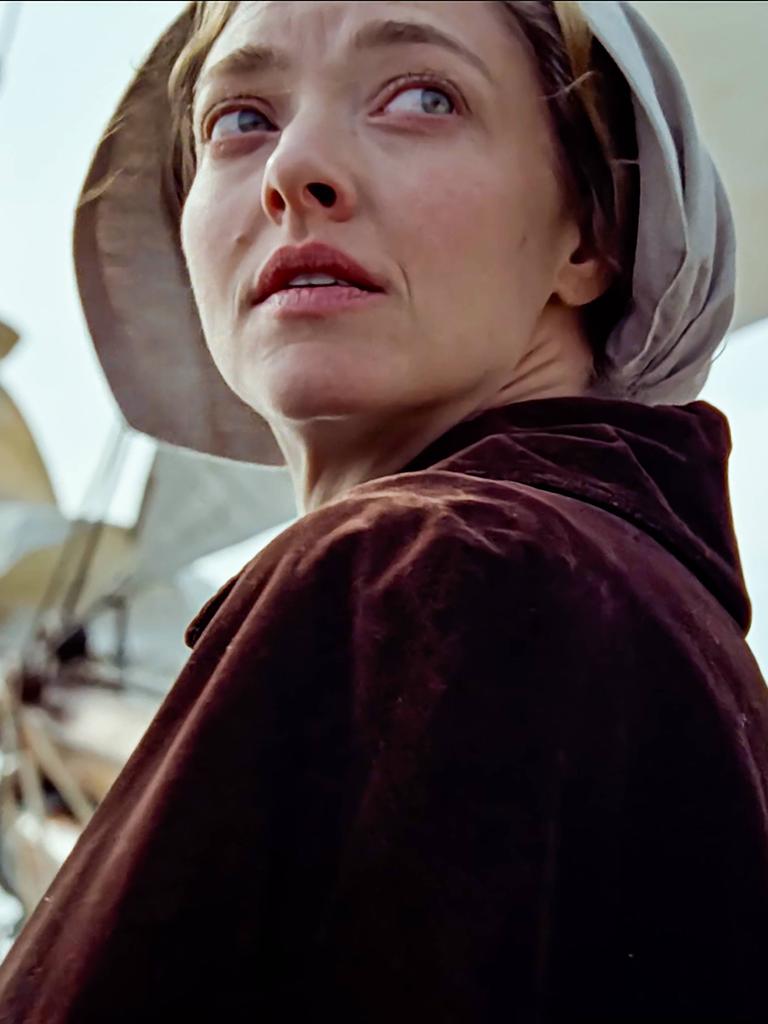 Die Hauptdarstellerin Amanda Seyfried in ihrer Rolle als Ann Lee dreht sich um. Im Hintergrund ist der Mast eines Bootes zu sehen, sie trägt eine traditionelle Kopfbedeckung. 