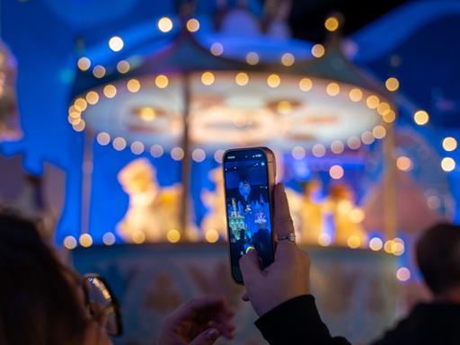 In einen Freizeitpark hält ein Kind ein Smartphone in die Höhe und macht ein Foto. Im Hintergrund ist verschwommen ein Fahrgeschäft. In einen Freizeitpark hält ein Kind ein Smartphone in die Höhe und macht ein Foto. Im Hintergrund ist verschwommen ein Fahrgeschäft.