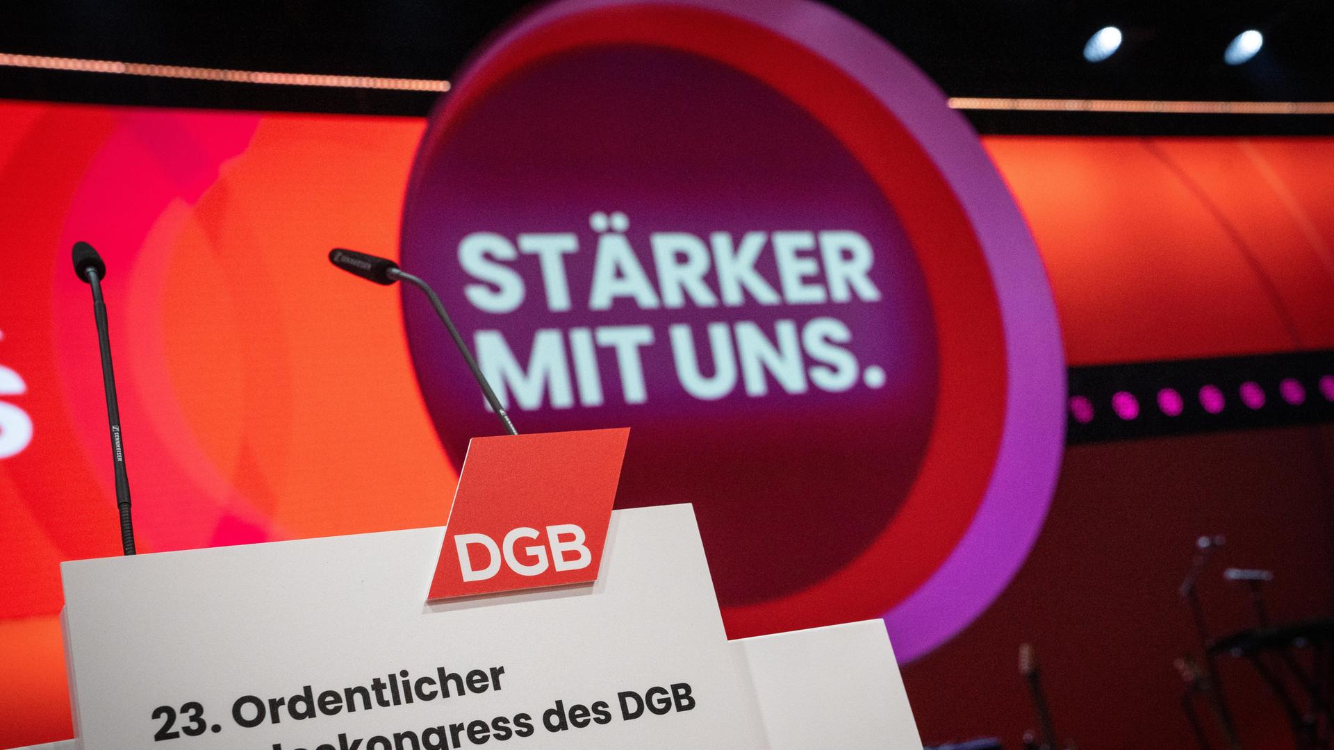 Auf einer Bühne steht ein Rednerpult, auf dem Schild davor steht "23. Ordentlicher Bundeskongress des DGB". Dahinter ist das Motto "Stärker mit uns" zu lesen.