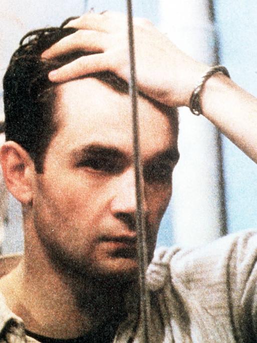 Ein Mann steht vor einem Spiegel und schaut sich ins Gesicht