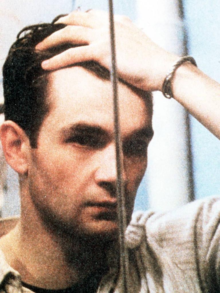 Ein Mann steht vor einem Spiegel und schaut sich ins Gesicht