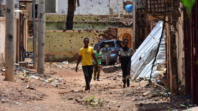 Im Sudan laufen mehrere Jugendliche eine von Zerstörungen und Einschüssen gezeichneten Straße. 