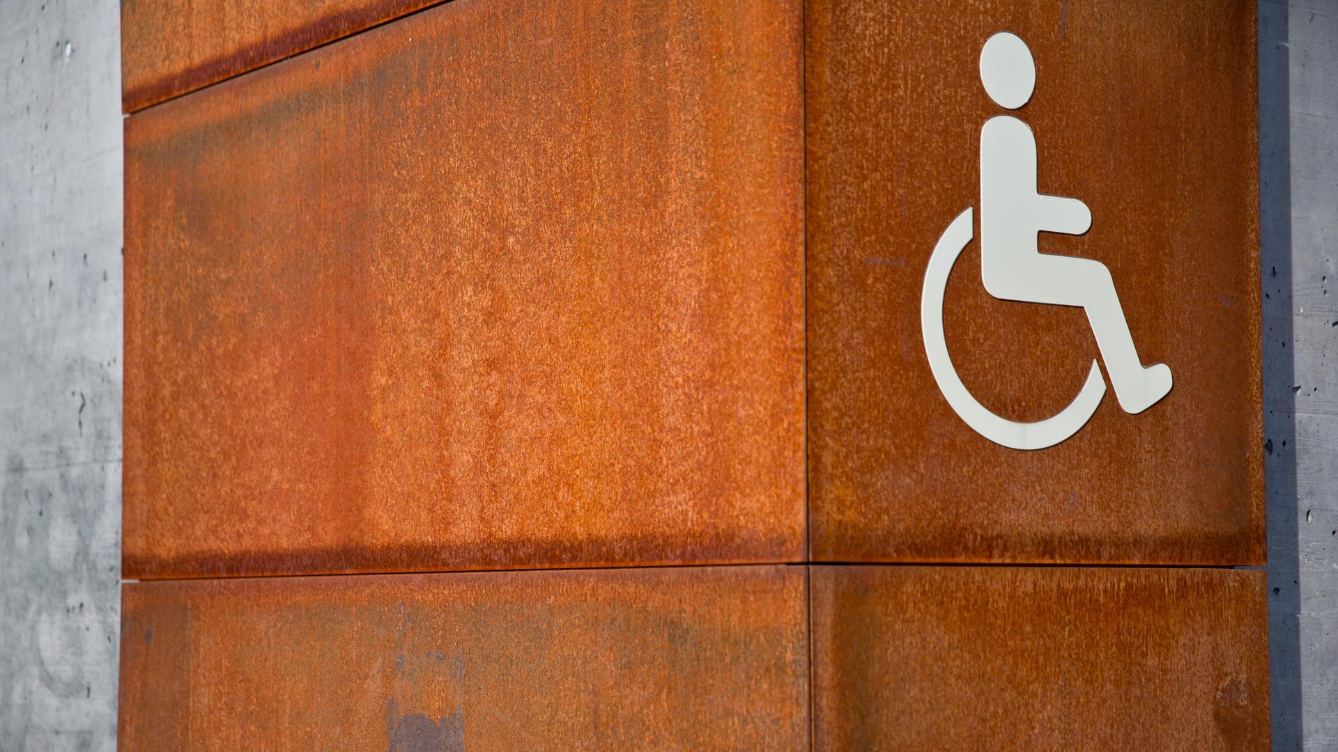 Das Bild zeigt das Piktogramm für Menschen mit Behinderte an einer Wand.