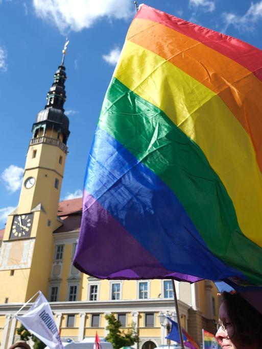 Eine Regenbogenflagge weht in der Luft bei blauem Himmel auf einem Platz in Bautzen beim CSD 2024. 